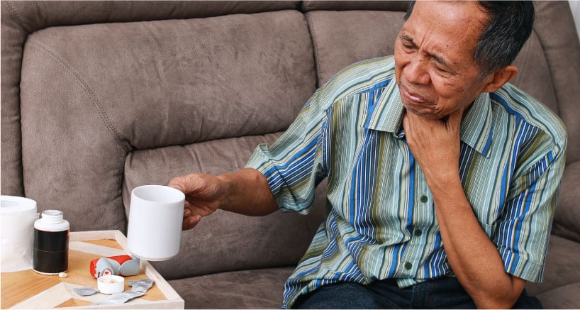 Man with Soar Throat Holding Warm Beverage