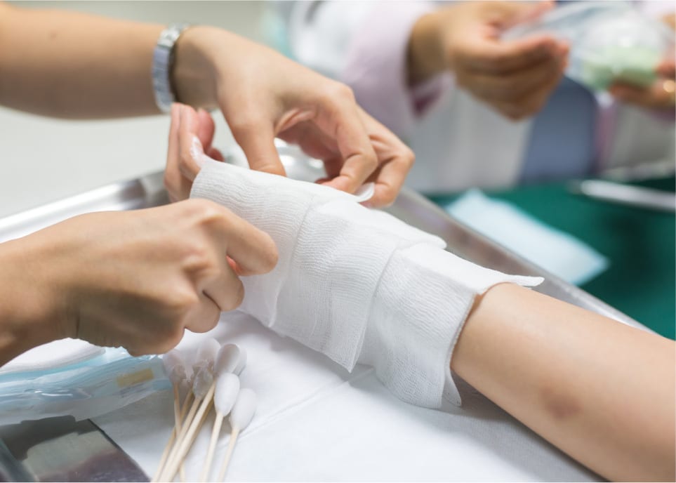 ER nurse dressing up injuries on a patient's arm